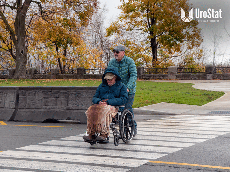 Man pushing another man in wheelchair, both with winter coats and wear on.