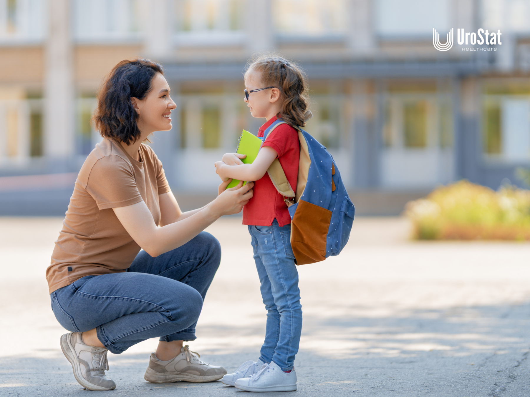 A woman crouches down to talk with a young girl wearing a backpack on a sunny sidewalk outside a building