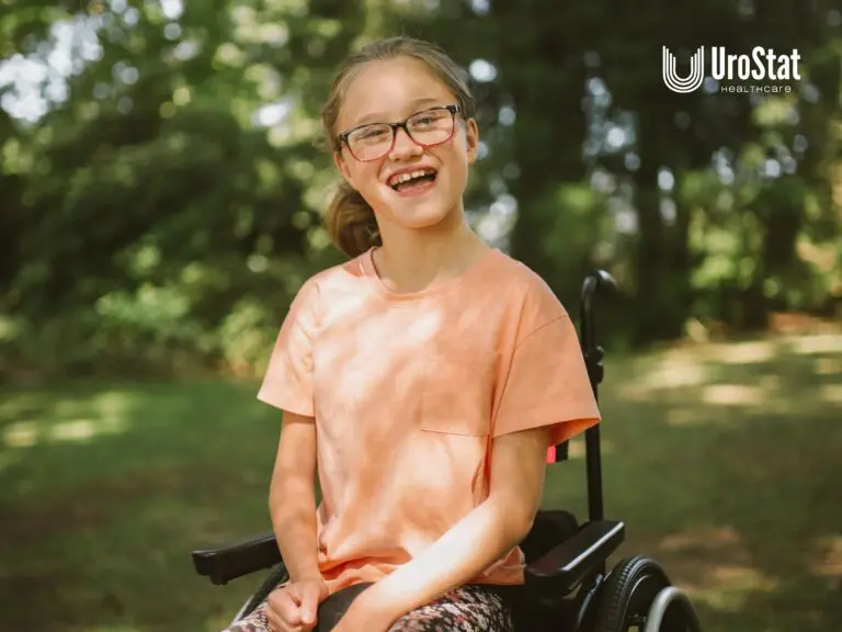 Smiling girl wearing glasses and a peach shirt seated in a wheelchair outdoors