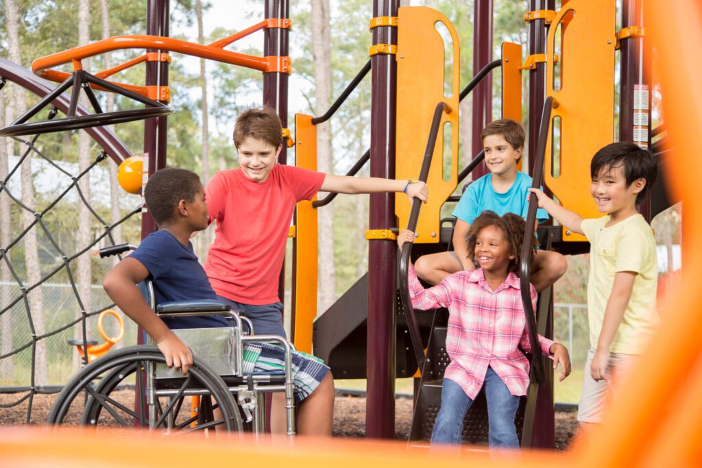 Multi-ethnic group of school children on school playground, one wheelchair.