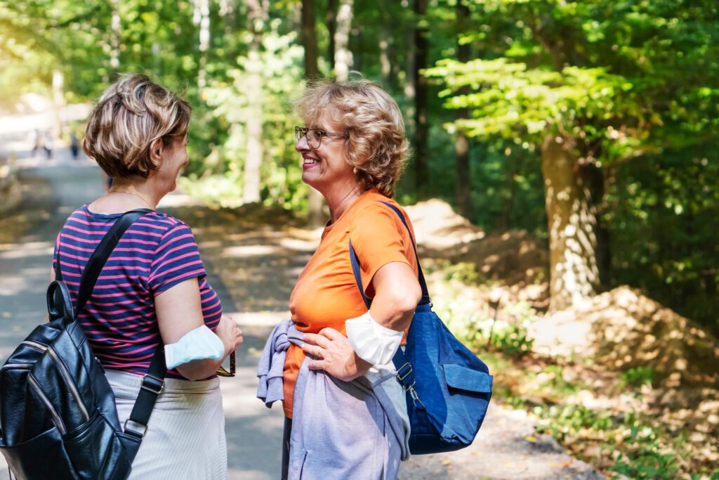 Two older female friends walking in nature together.