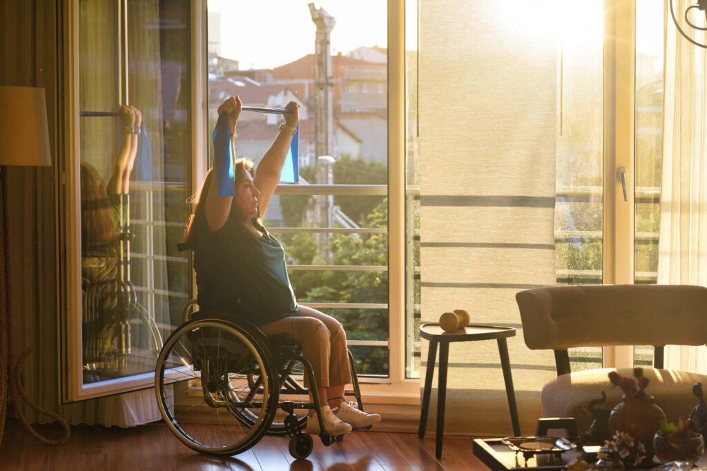 Woman in a wheelchair exercising with a resistance band at home.