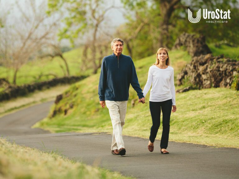 Older man and woman holding hands and walking outdoors in nature.