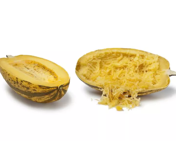 Twice baked spaghetti squash halved and on a white background