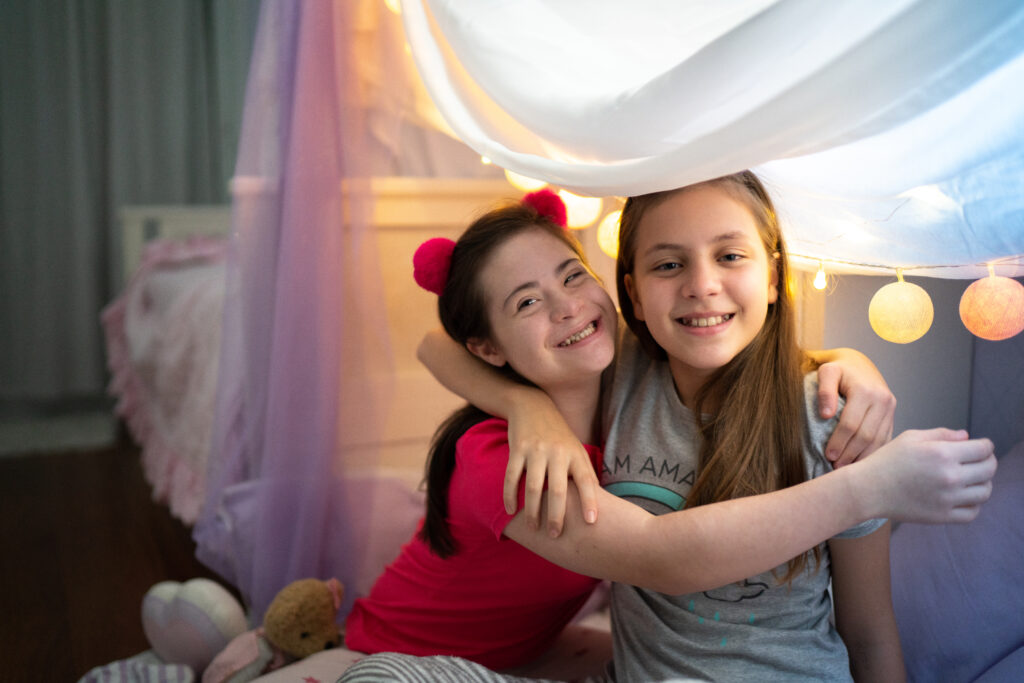 Girl with special needs with her arm around her friend at a sleepover.