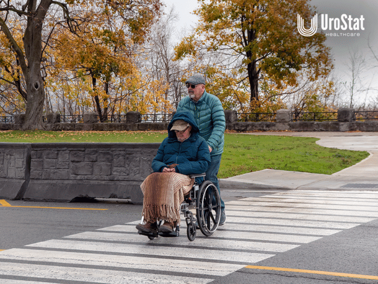 Man pushing another man in wheelchair, both with winter coats and wear on.