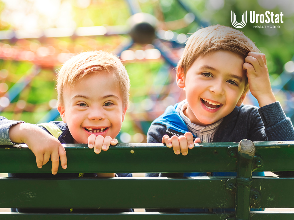 Two kids looking over bench and smiling, one of which has down syndrome