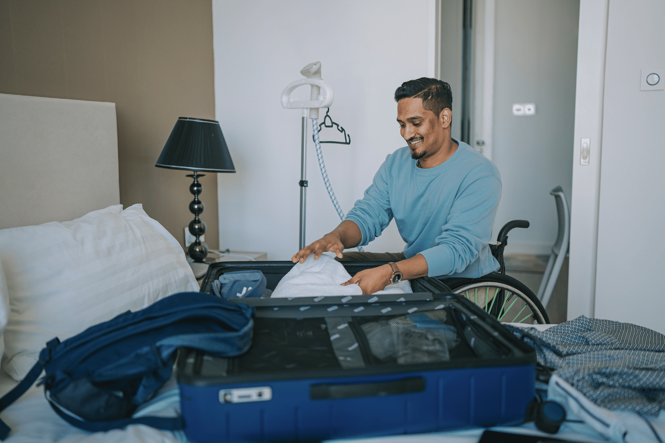 Man in wheelchair packing his suitcase that is on the bed