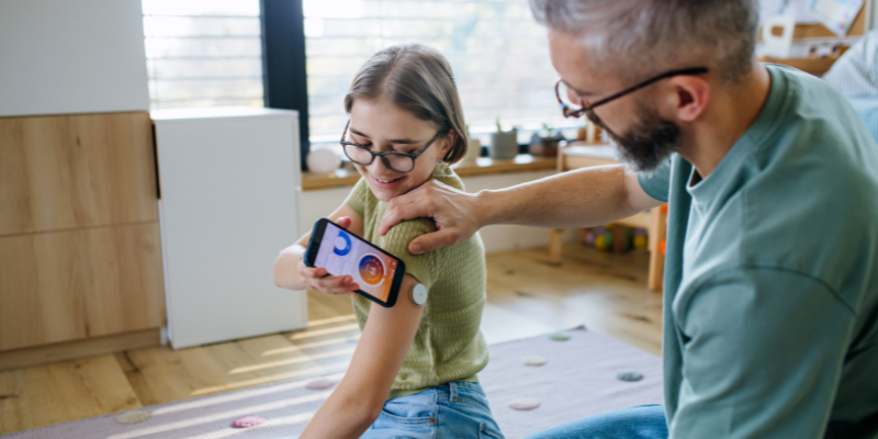 Father helping daughter scan her CGM with smartphone app