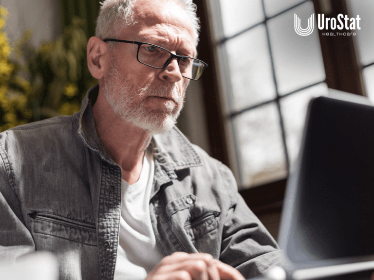 Image of older man looking intently at computer screen in the foreground