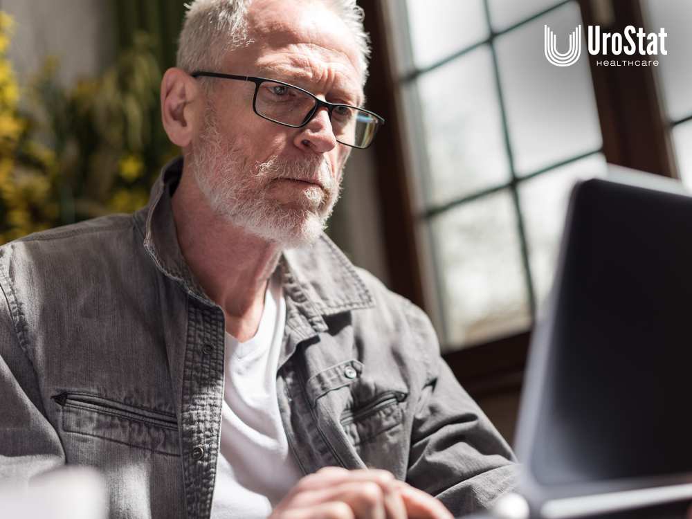 Image of older man looking intently at computer screen in the foreground