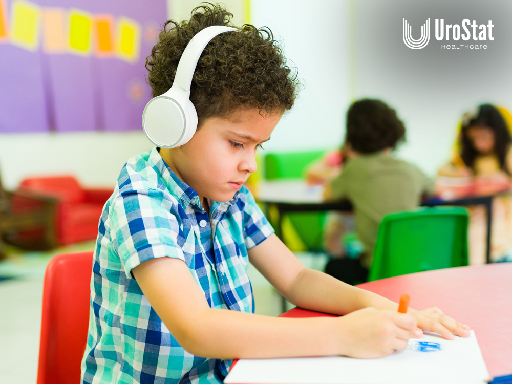 Child sitting at desk in school with headphones on and writing.