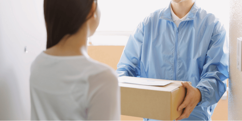 Image shows woman receiving box from delivery person