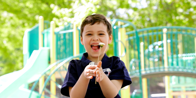 Boy holding a flower and smiling at the park