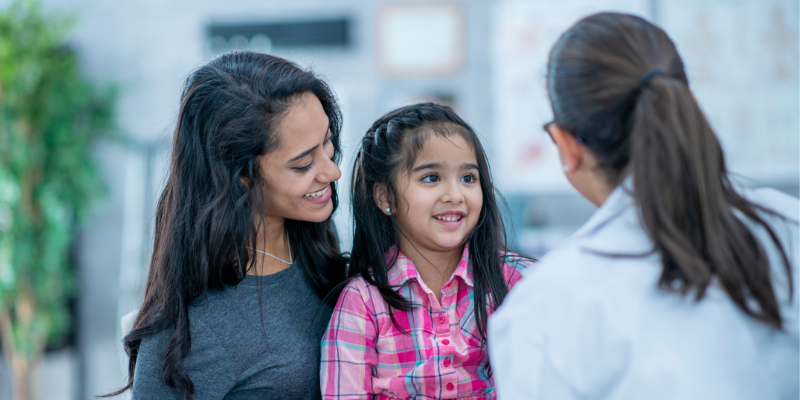 Mother and daughter speaking with female doctor