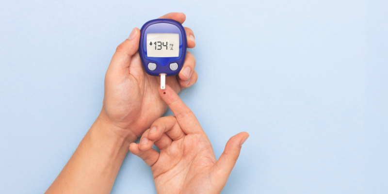 Person with tiny drop of blood on their finger from their finger prick glucose test, holding glucose meter