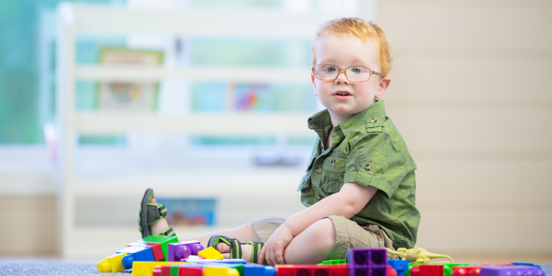 Toddler boy sitting on floor in front of building blocks