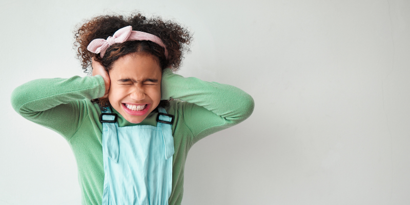 Child covering their ears and looking upset